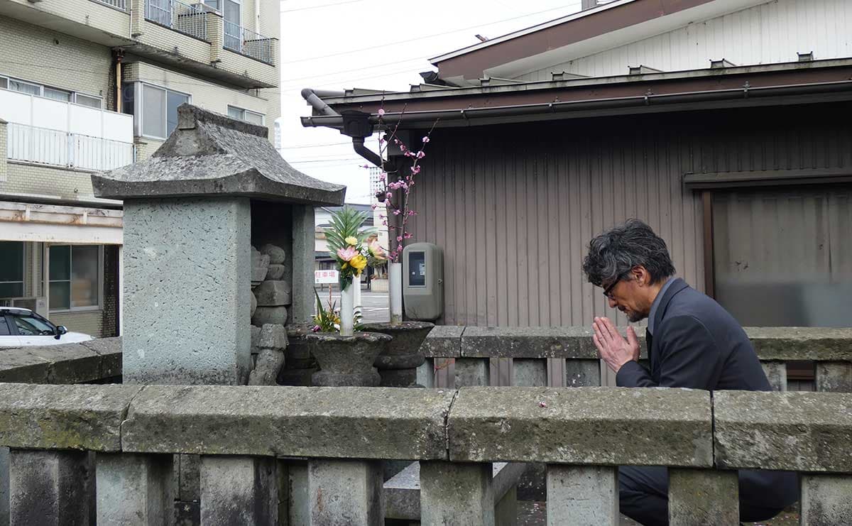 西光寺の墓に手を合わせる山口馬木也さん